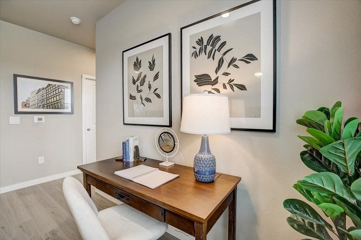 Dedicated desk nook with lamp lighting, framed artwork, and a comfortable upholstered chair.